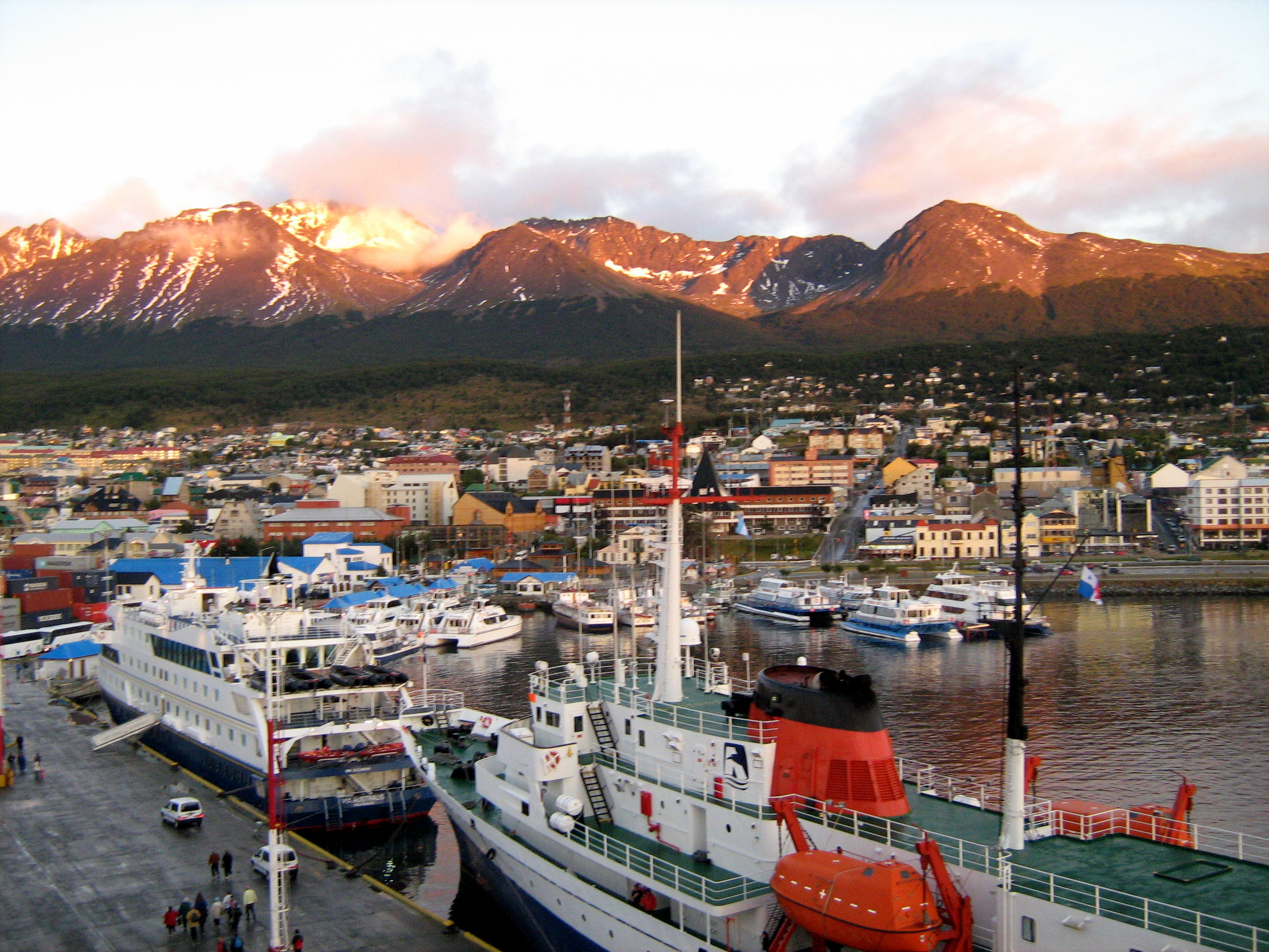Vue du port d'Ushuaia (Argentine) en Terre de Feu, avec navires et chaîne montagneuse en arrière-plan.
